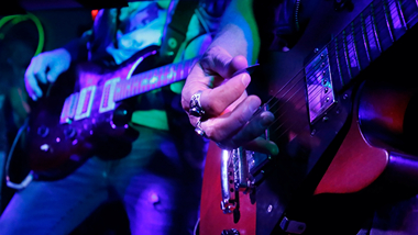 two guitars with hands strumming their strings